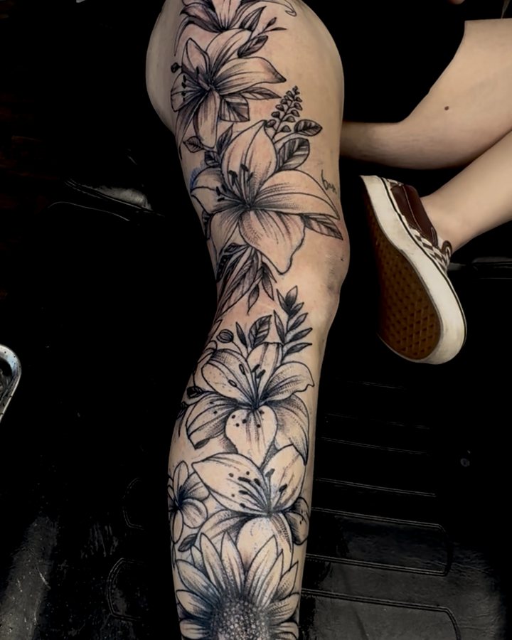 Black-and-grey floral leg piece — lilies and a sunflower down the leg.