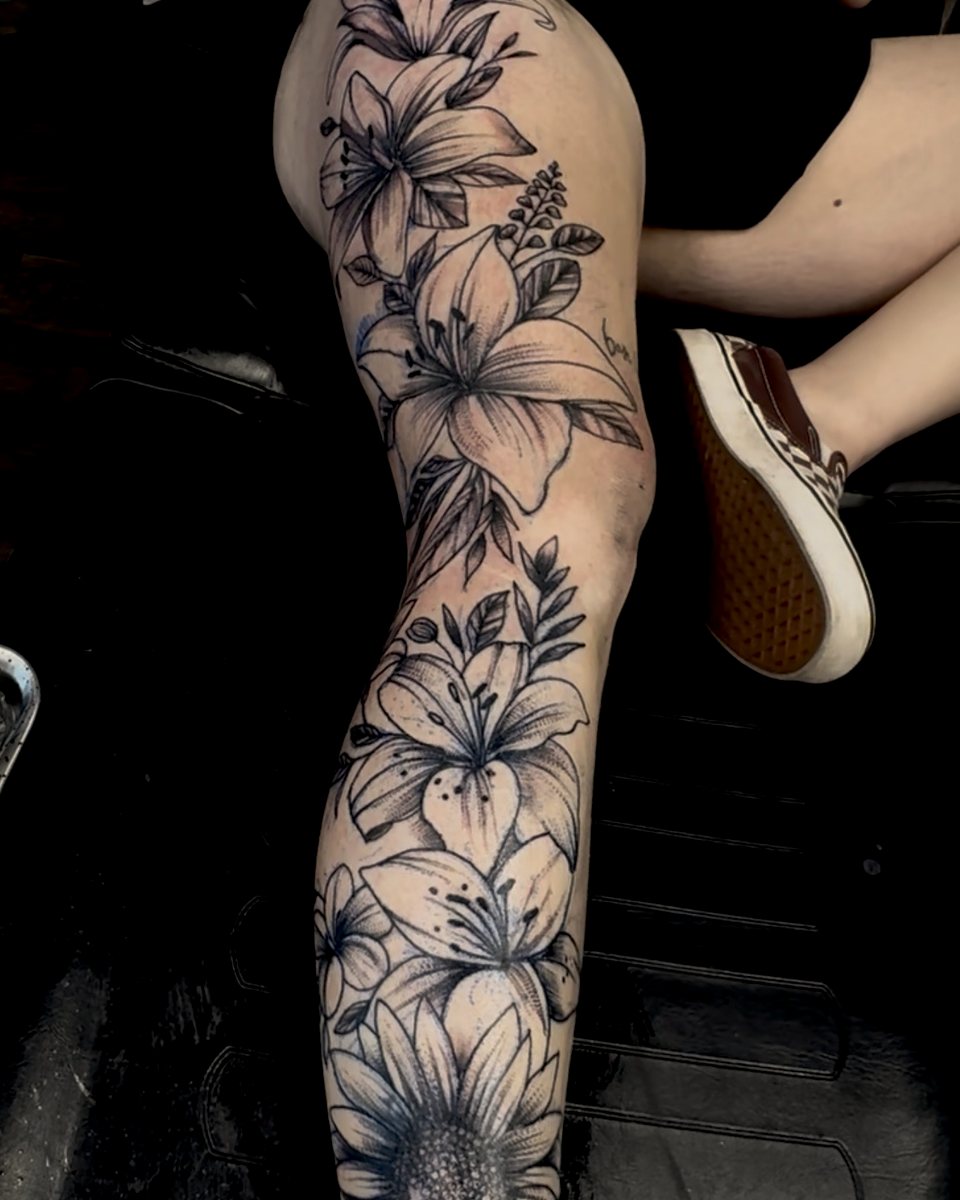 Black-and-grey floral leg piece — lilies and a sunflower down the leg.