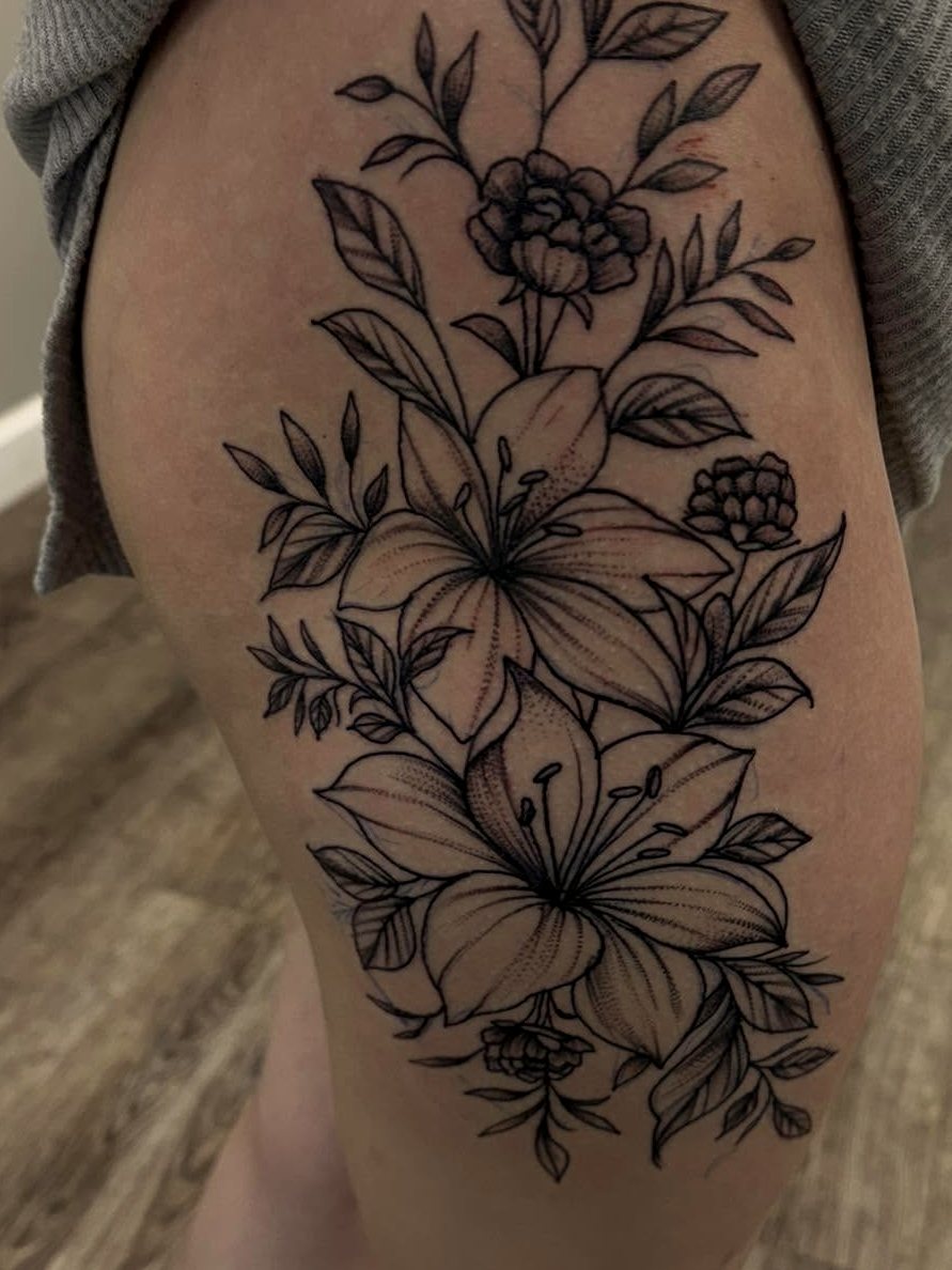 Black-and-grey fineline lily tattoo on a thigh.